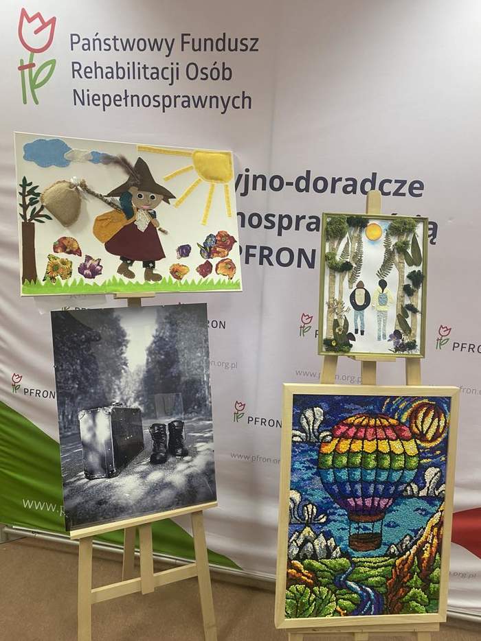 Pokaż zdjęcie: Na tle baneru reklamującego CIDON znajdują się dwie sztalugi z 4 kolorowymi pracami