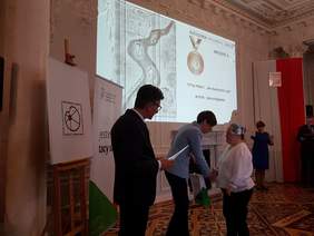 Pokaż zdjęcie: Wręczenie nagród laureatowi konkursu plastycznego „Sztuka Osób Niepełnosprawnych” za zdobycie II miejsca w kategorii rysunek i grafika przez Annę Skupień, dyrektora Oddziału Wielkopolskiego PFRON oraz Krzysztofa Pawlaka, dyrektora Liceum w Kościelcu